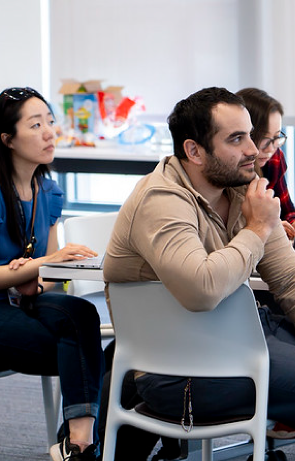 3 people watching a speaker at a seminar